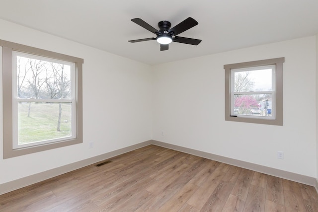 empty room with ceiling fan, light wood-style floors, visible vents, and baseboards