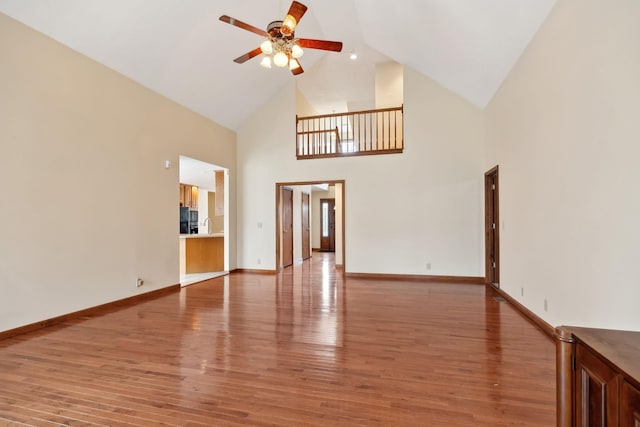 unfurnished living room featuring light wood finished floors, baseboards, ceiling fan, lofted ceiling, and a sink