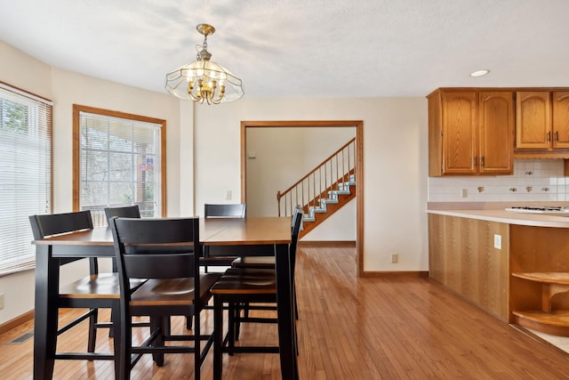 dining room featuring a notable chandelier, recessed lighting, stairway, light wood-style floors, and baseboards