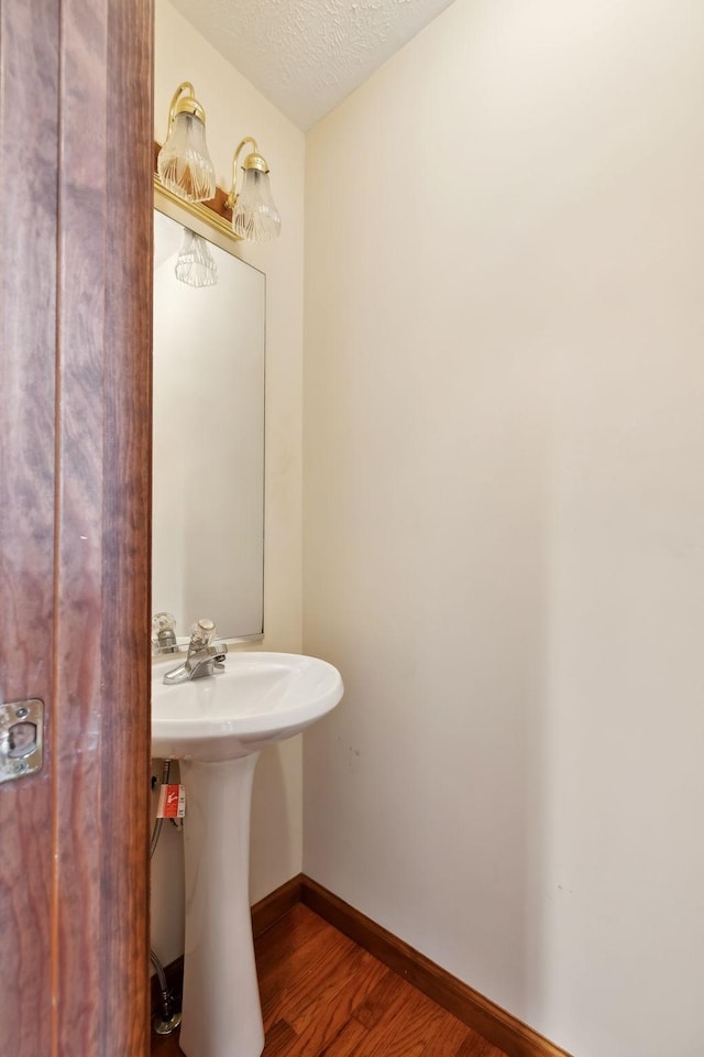 bathroom with a sink, baseboards, a textured ceiling, and wood finished floors