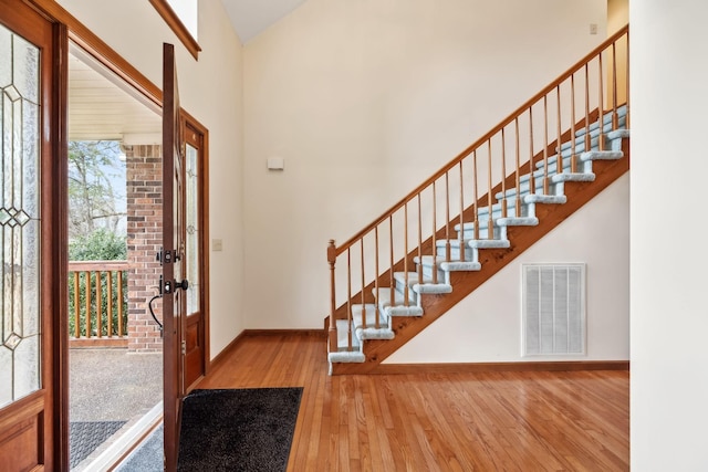 entrance foyer featuring visible vents, wood-type flooring, baseboards, and stairway