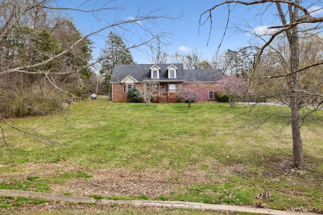 new england style home with a front yard and brick siding