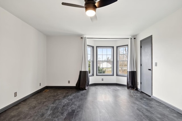spare room featuring dark wood-type flooring, baseboards, and ceiling fan