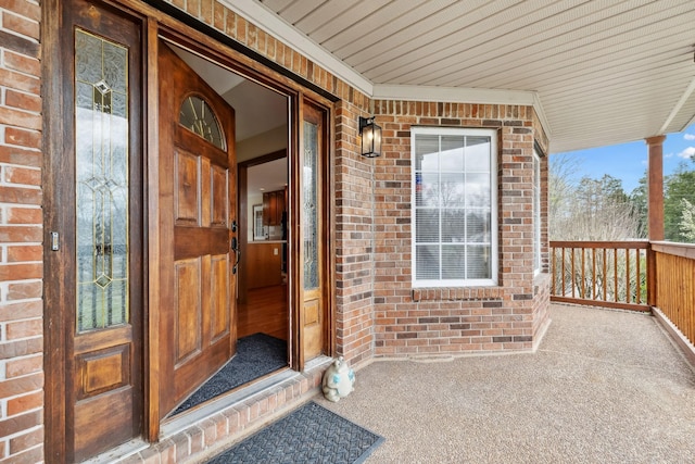 property entrance featuring a porch and brick siding