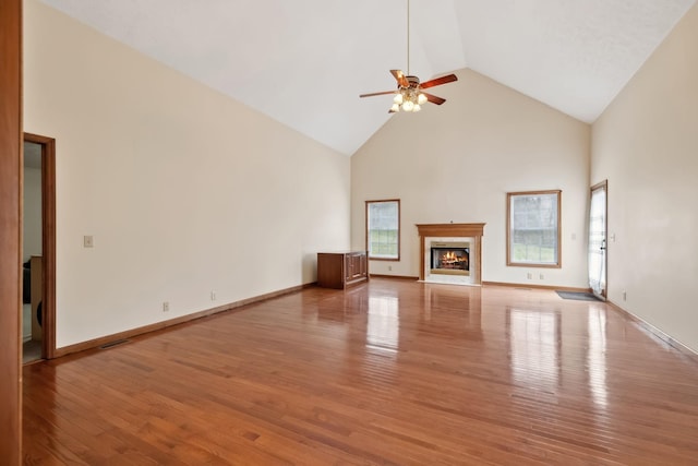 unfurnished living room featuring wood finished floors, a ceiling fan, baseboards, a premium fireplace, and high vaulted ceiling