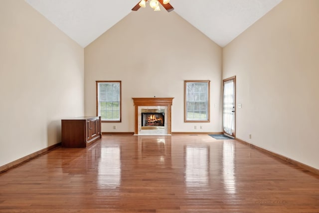 unfurnished living room with ceiling fan, high vaulted ceiling, wood finished floors, and a fireplace