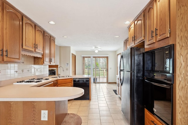 kitchen with black appliances, a peninsula, light countertops, light tile patterned floors, and decorative backsplash