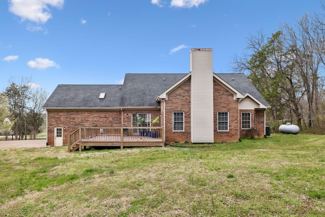 rear view of house featuring a deck, a yard, and brick siding