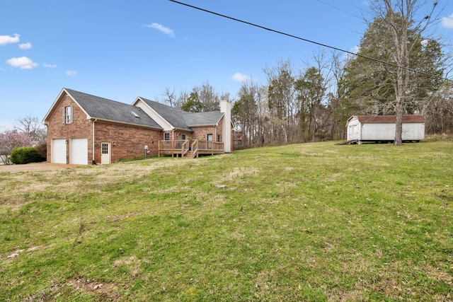 view of yard with a deck, a storage shed, an outbuilding, and driveway