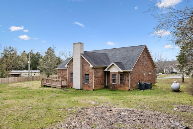back of property featuring brick siding, fence, a wooden deck, central AC unit, and a lawn