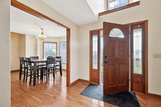 entrance foyer featuring visible vents, baseboards, a notable chandelier, and light wood-style flooring