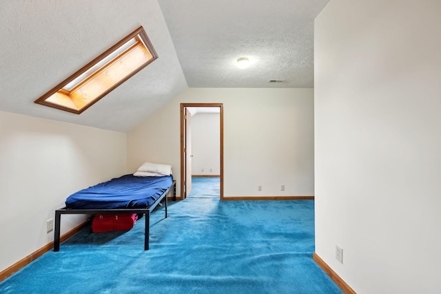 carpeted bedroom featuring lofted ceiling with skylight, visible vents, a textured ceiling, and baseboards
