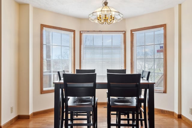 dining space featuring a chandelier, light wood-style flooring, and baseboards