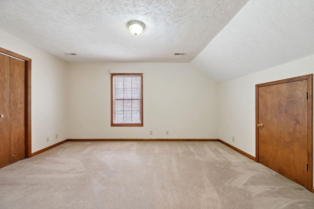 unfurnished bedroom featuring visible vents, light colored carpet, baseboards, and vaulted ceiling