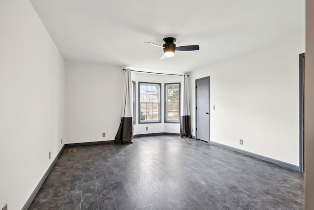 spare room featuring baseboards, dark wood-type flooring, and ceiling fan