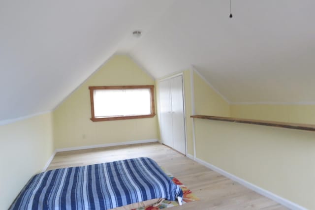 unfurnished bedroom featuring vaulted ceiling, wood finished floors, and baseboards
