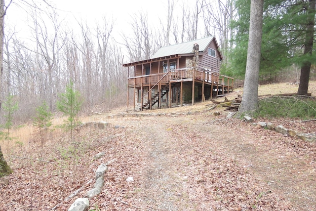 exterior space featuring metal roof, driveway, a deck, and stairs