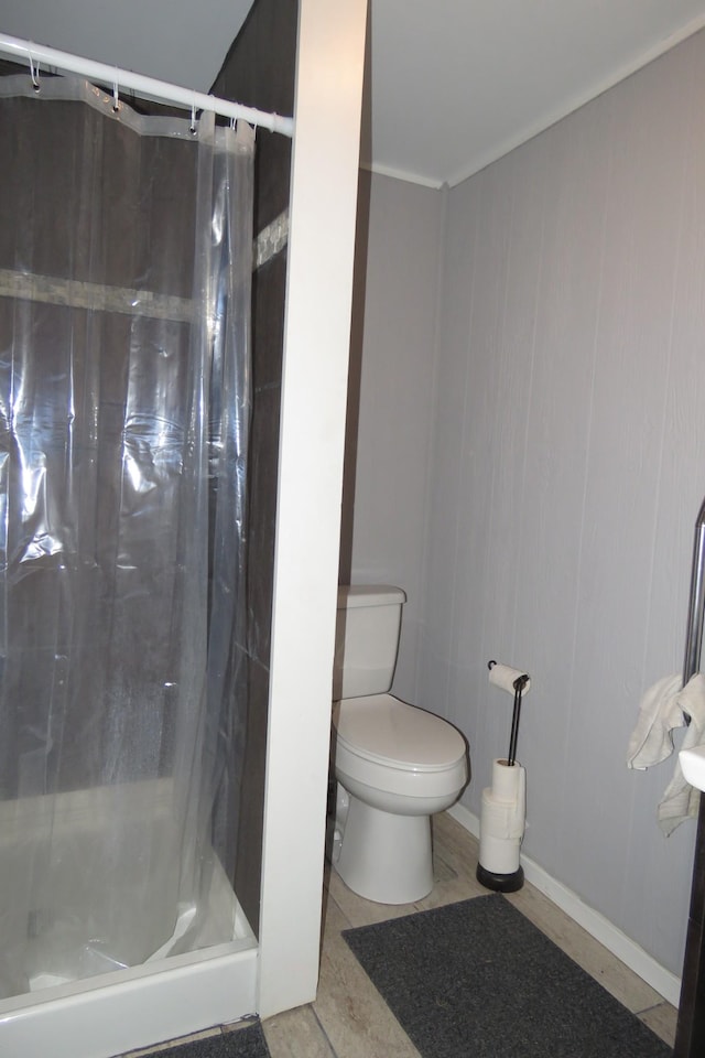 full bathroom featuring toilet, baseboards, and a stall shower