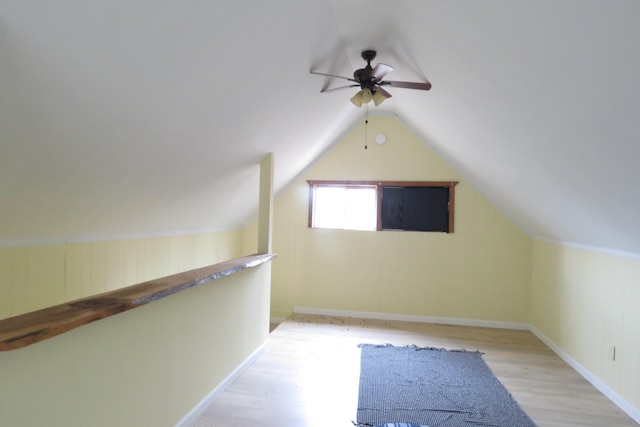 additional living space featuring vaulted ceiling, wood finished floors, baseboards, and ceiling fan