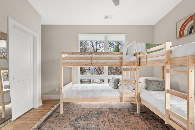 bedroom with visible vents, baseboards, and wood finished floors