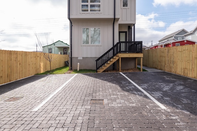 rear view of house with crawl space, uncovered parking, board and batten siding, and fence private yard