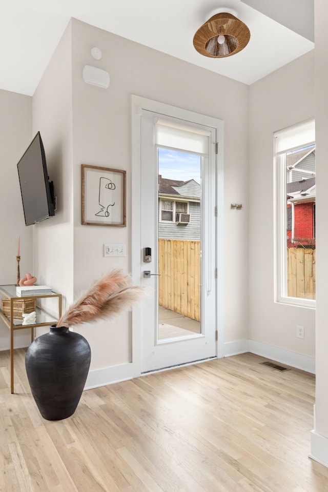 doorway to outside with a wealth of natural light, light wood-style floors, baseboards, and visible vents