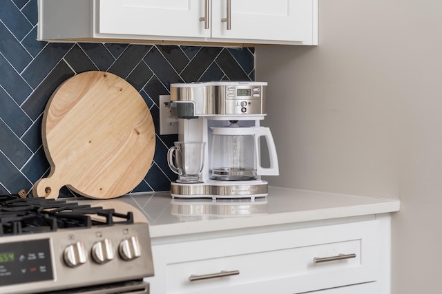 room details with tasteful backsplash, light countertops, white cabinetry, and stainless steel gas range oven