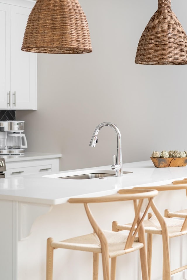 interior space with a sink, light countertops, white cabinets, and a kitchen bar