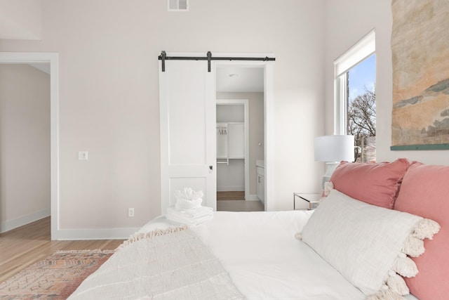 bedroom featuring wood finished floors, baseboards, and a barn door