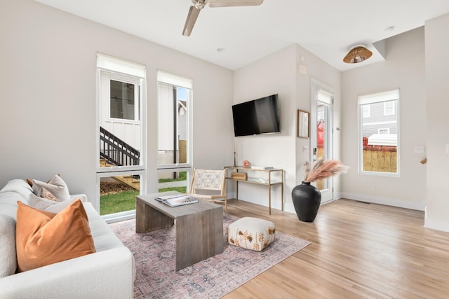 living area featuring wood finished floors, baseboards, and a ceiling fan