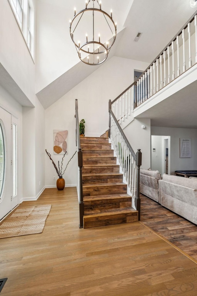 entryway with stairs, visible vents, a high ceiling, and wood finished floors