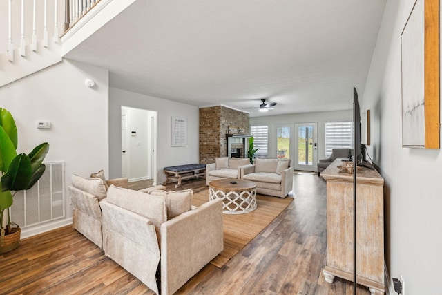 living room featuring a fireplace, ceiling fan, visible vents, and wood finished floors