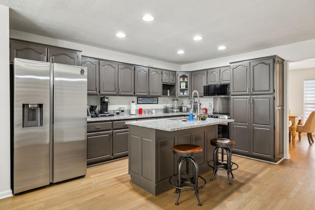 kitchen with light stone countertops, light wood-style flooring, stainless steel fridge, and a kitchen island