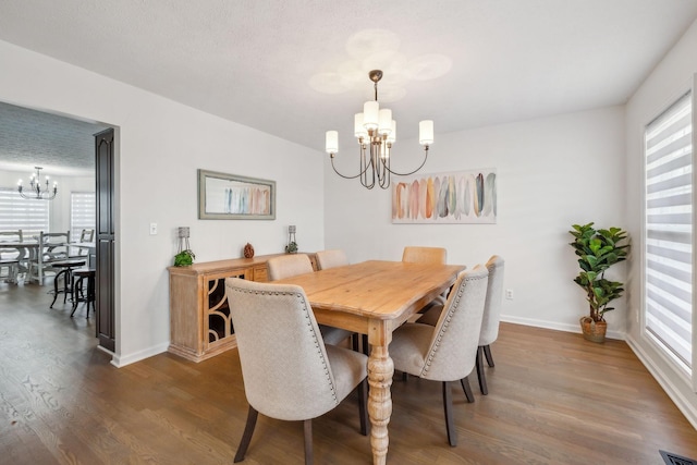 dining room featuring dark wood-style floors, a healthy amount of sunlight, baseboards, and a chandelier