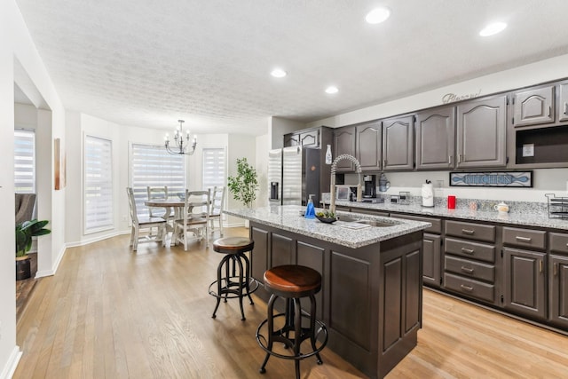 kitchen featuring a center island, a kitchen bar, light wood-style floors, and stainless steel fridge