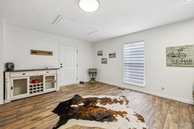 interior space with baseboards, attic access, a textured ceiling, and wood finished floors