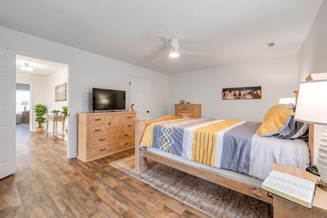 bedroom with a ceiling fan, visible vents, and wood finished floors