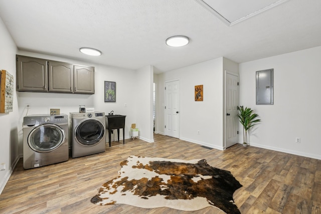 clothes washing area featuring independent washer and dryer, cabinet space, wood finished floors, and electric panel