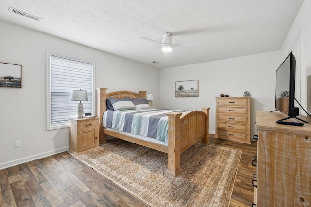 bedroom with baseboards, visible vents, wood finished floors, and a textured ceiling