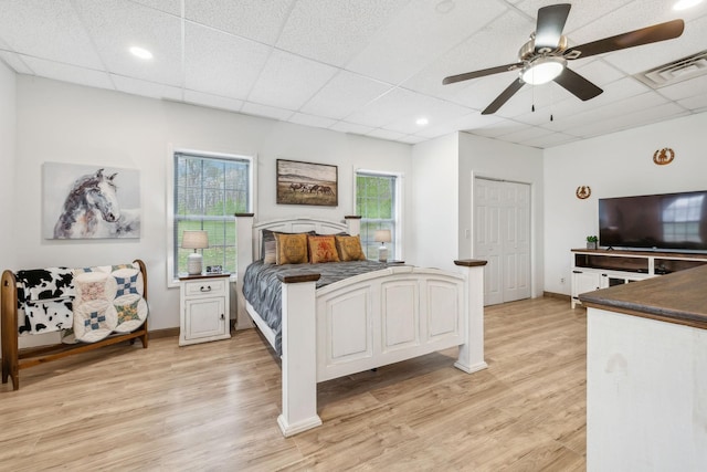 bedroom featuring a drop ceiling, light wood-style flooring, baseboards, and visible vents
