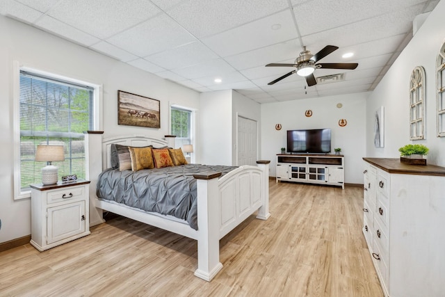 bedroom featuring a drop ceiling, visible vents, baseboards, and light wood-type flooring