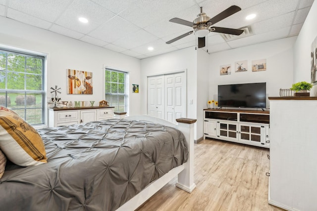 bedroom with a closet, light wood-style floors, ceiling fan, recessed lighting, and a paneled ceiling