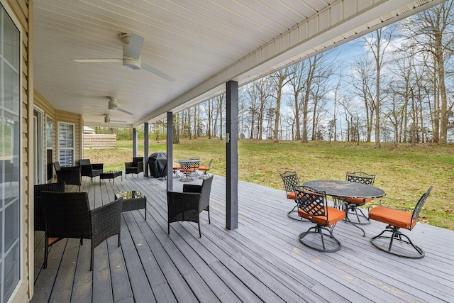 wooden deck featuring outdoor lounge area, a lawn, outdoor dining area, and a ceiling fan