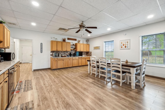 dining area with baseboards, a drop ceiling, light wood-style floors, visible vents, and a ceiling fan