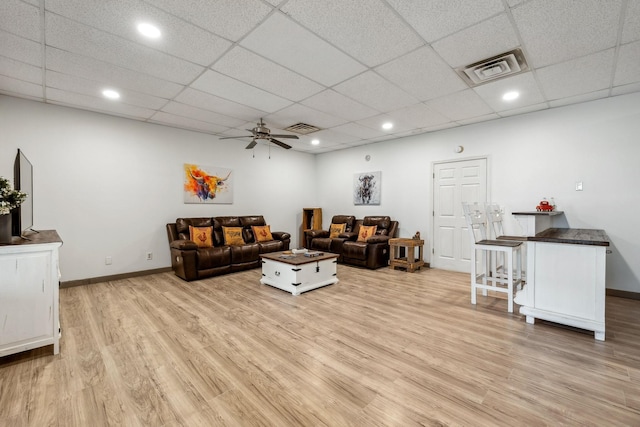 living room featuring baseboards, visible vents, a ceiling fan, and light wood finished floors