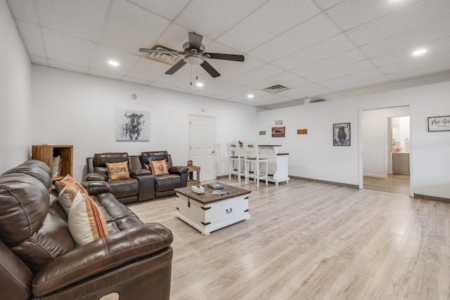 living area with visible vents, a paneled ceiling, a ceiling fan, and light wood finished floors