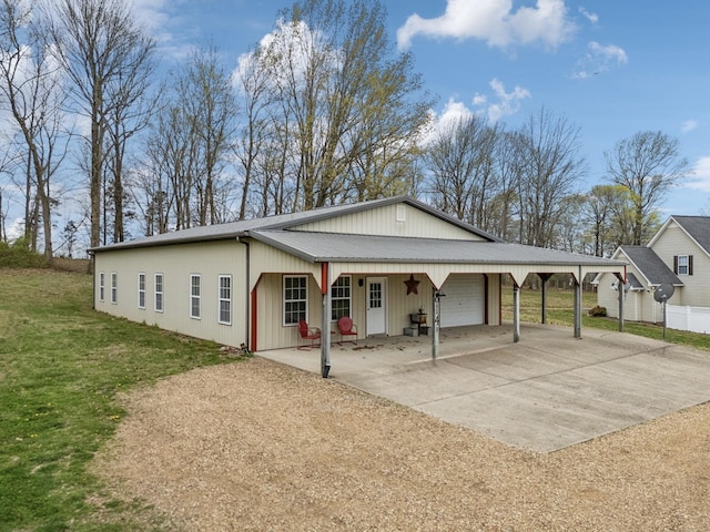 view of front of house featuring metal roof, a garage, concrete driveway, a front yard, and a carport