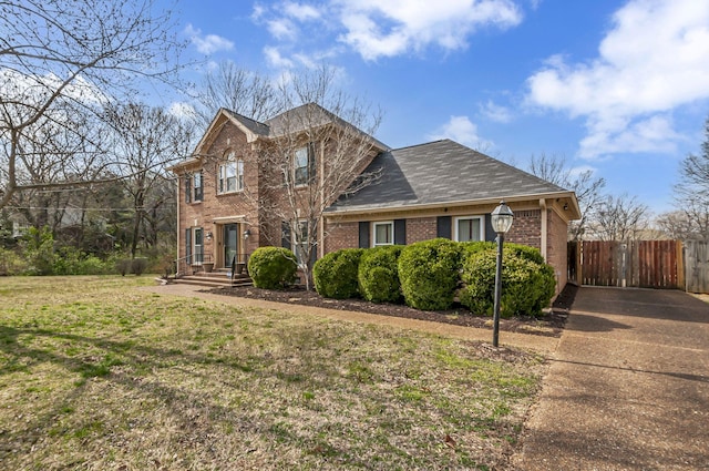 view of front of house with brick siding, concrete driveway, a front lawn, and fence