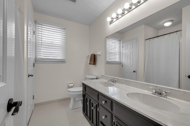 full bathroom featuring double vanity, toilet, baseboards, and a sink