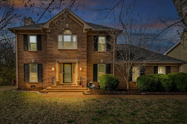 view of front of property featuring brick siding, a chimney, and a front lawn